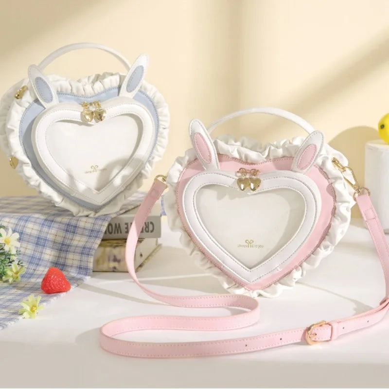Two shoulder bags designed as peach heart shapes with white lace and pink straps, featuring rabbit ear details and a zipper closure.